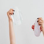 Female hands holding reusable and disposable sanitary pads on a white background.